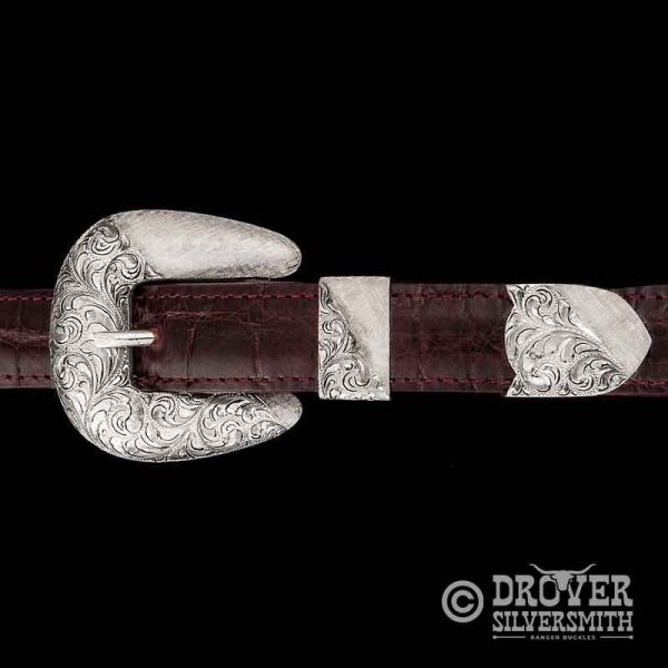 This three piece silver belt buckle set combines very traditional hand engraving with a hand engraved crossgrain texture for a sophisticated touch!